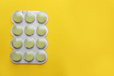 Photo of Blister with cough drops on yellow background, top view. Space for text