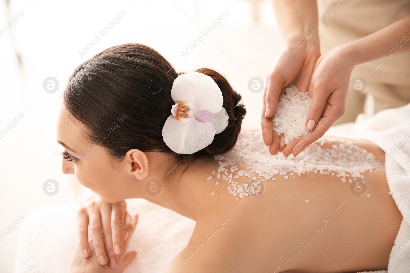 Photo of Beautiful young woman having massage with body scrub in spa salon