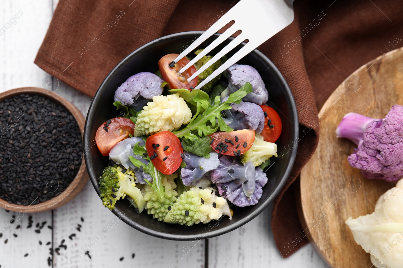 Photo of Delicious salad with cauliflower and tomato served on white wooden table, flat lay