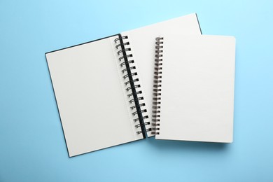 Two notebooks on light blue background, top view