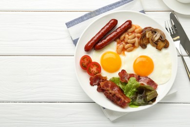 Delicious breakfast with sunny side up eggs served on white wooden table, top view