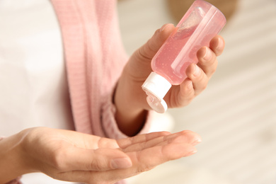 Woman applying antiseptic gel at home, closeup