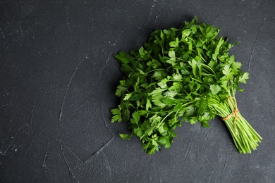 Photo of Bunch of fresh green parsley on dark background, view from above. Space for text