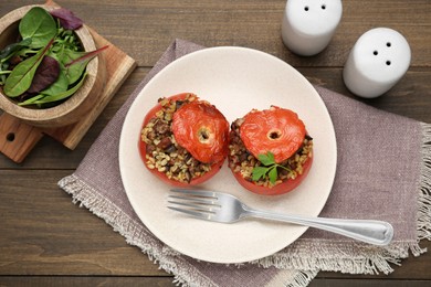 Photo of Delicious stuffed tomatoes with minced beef, bulgur and mushrooms served on wooden table, flat lay