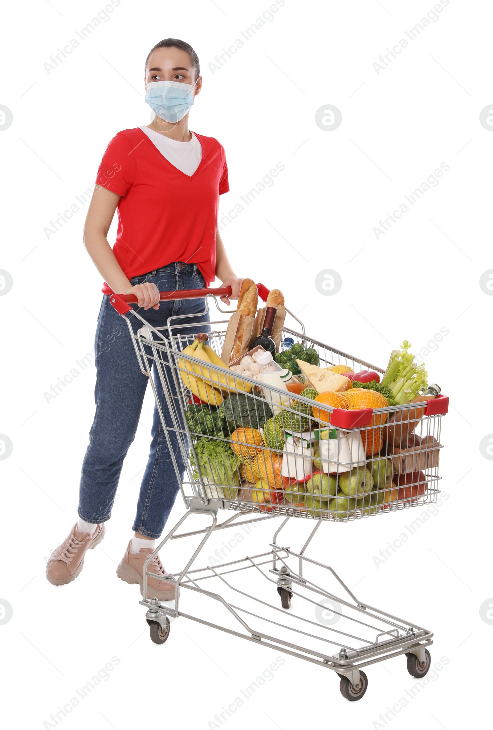 Photo of Woman with protective mask and shopping cart full of groceries on white background