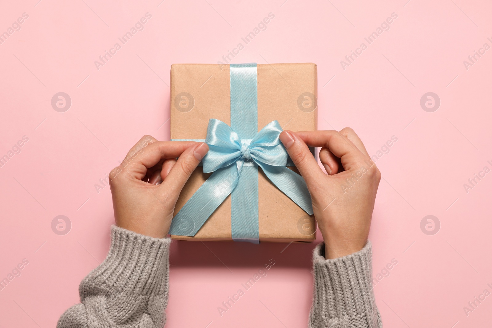 Photo of Woman with Christmas gift on pink background, top view