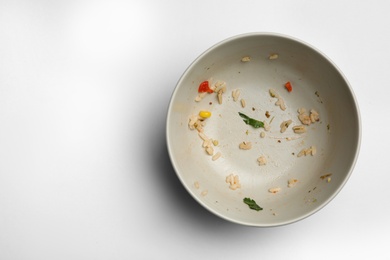 Photo of Dirty bowl with food leftovers on white background, top view