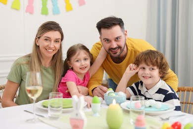 Photo of Happy family celebrating Easter at served table in room