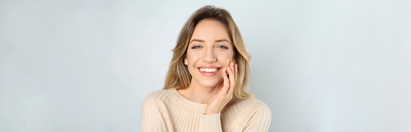 Portrait of happy young woman with beautiful blonde hair and charming smile on light background. Horizontal banner design