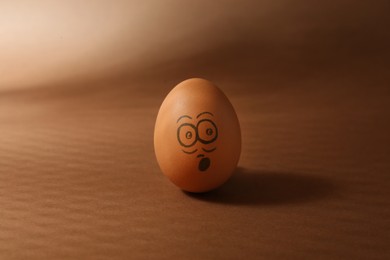 Photo of Egg with drawn surprised face on brown background