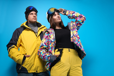 Photo of Couple wearing stylish winter sport clothes on light blue background, low angle view