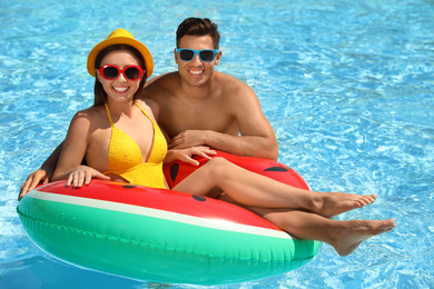 Happy couple with inflatable ring in swimming pool. Summer vacation