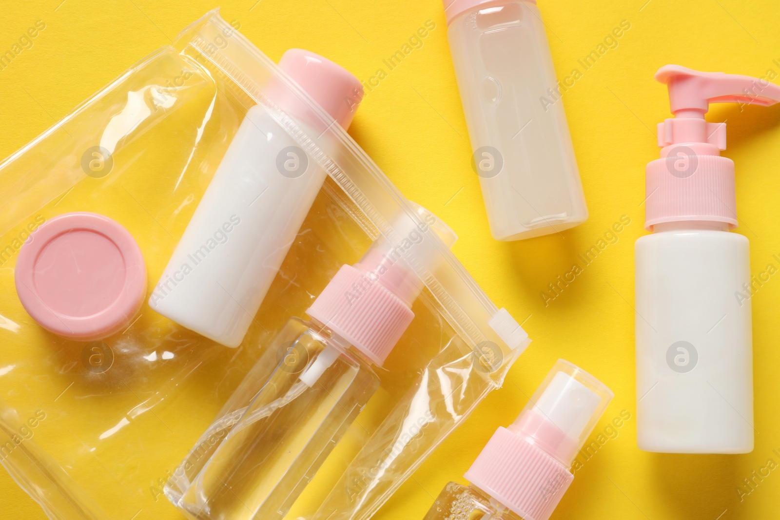 Photo of Plastic bag with cosmetic travel kit on yellow background, flat lay. Bath accessories