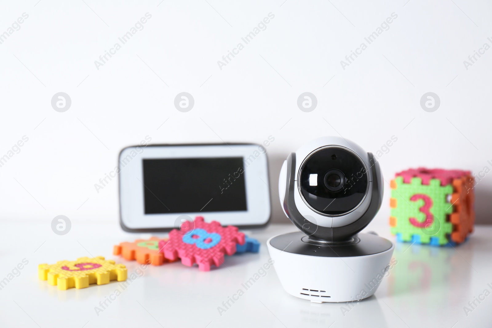 Photo of Modern CCTV security camera, monitor and child puzzle on table against white background. Space for text