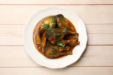 Photo of Tasty fish curry on white wooden table, top view. Indian cuisine