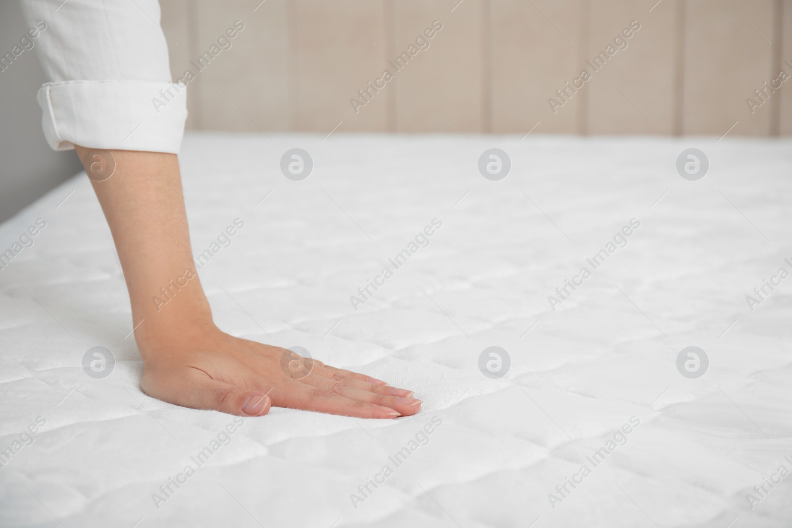 Photo of Woman touching soft white mattress indoors, closeup. Space for text