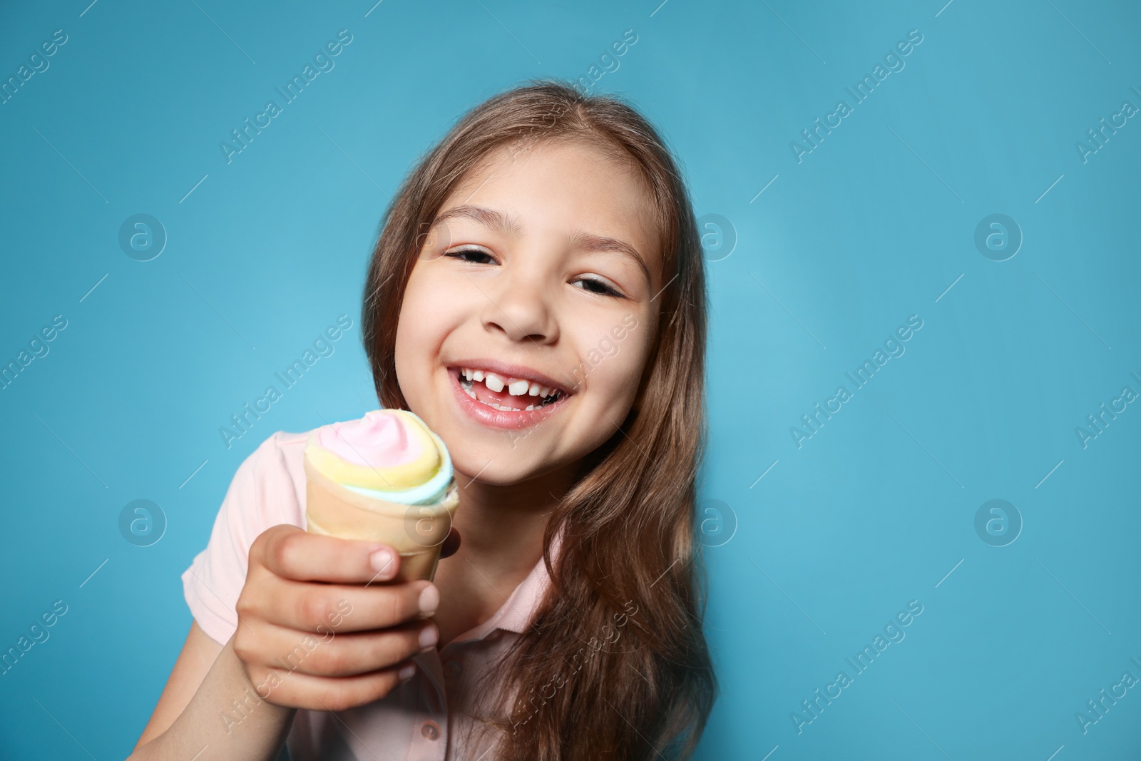 Photo of Cute little girl with delicious ice cream against color background, space for text