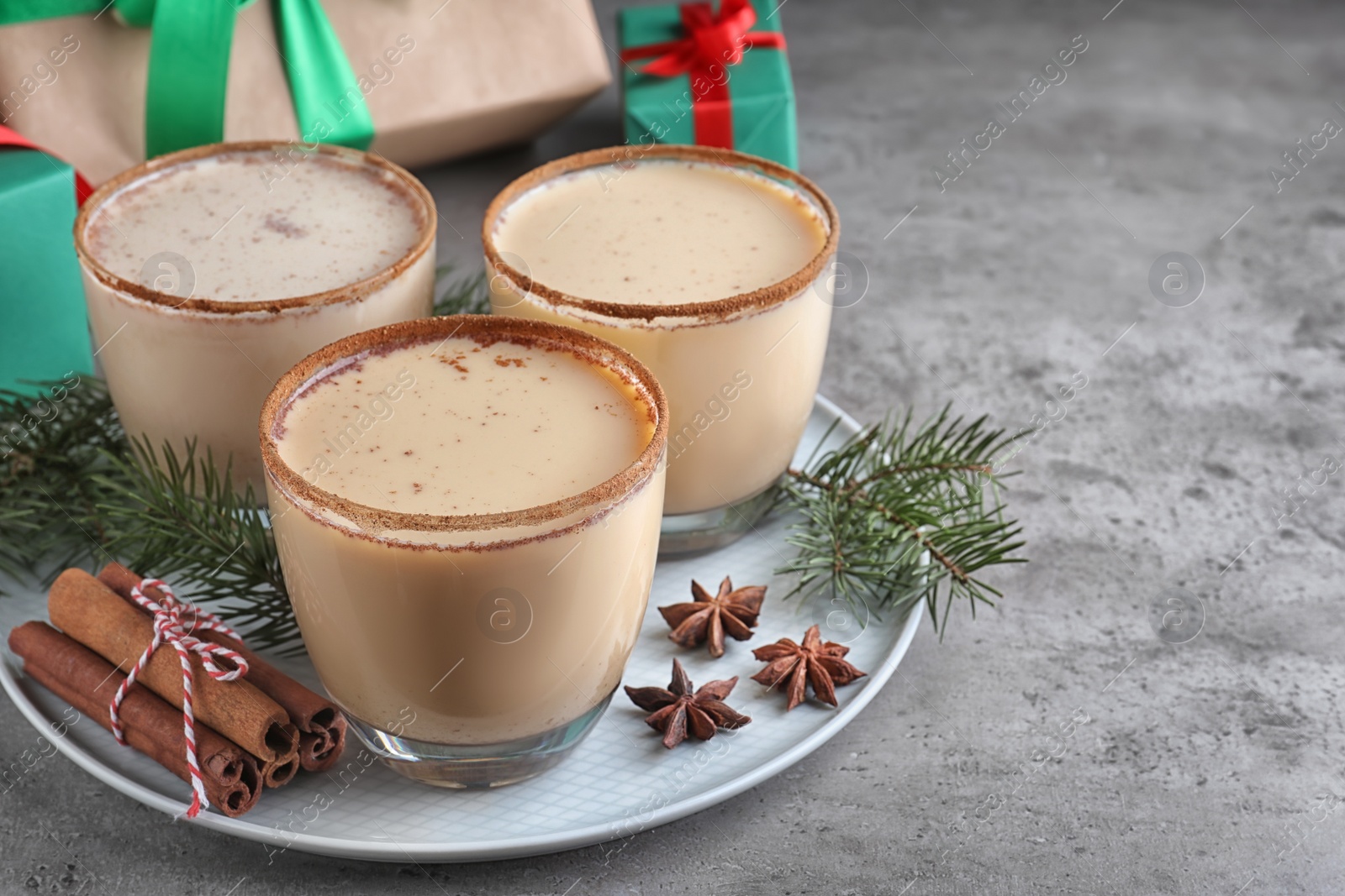 Photo of Delicious Christmas liqueur and ingredients on grey table, closeup