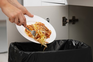 Photo of Woman throwing pasta into bin indoors, closeup