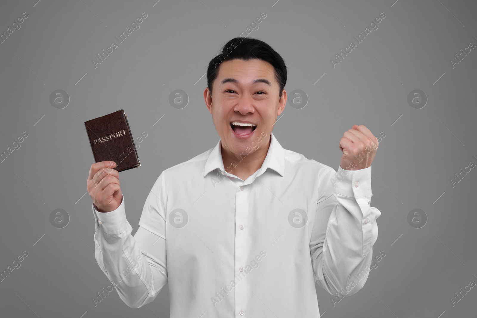 Photo of Immigration. Excited man with passport on grey background