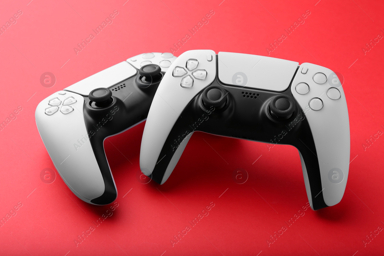 Photo of Two wireless game controllers on red background