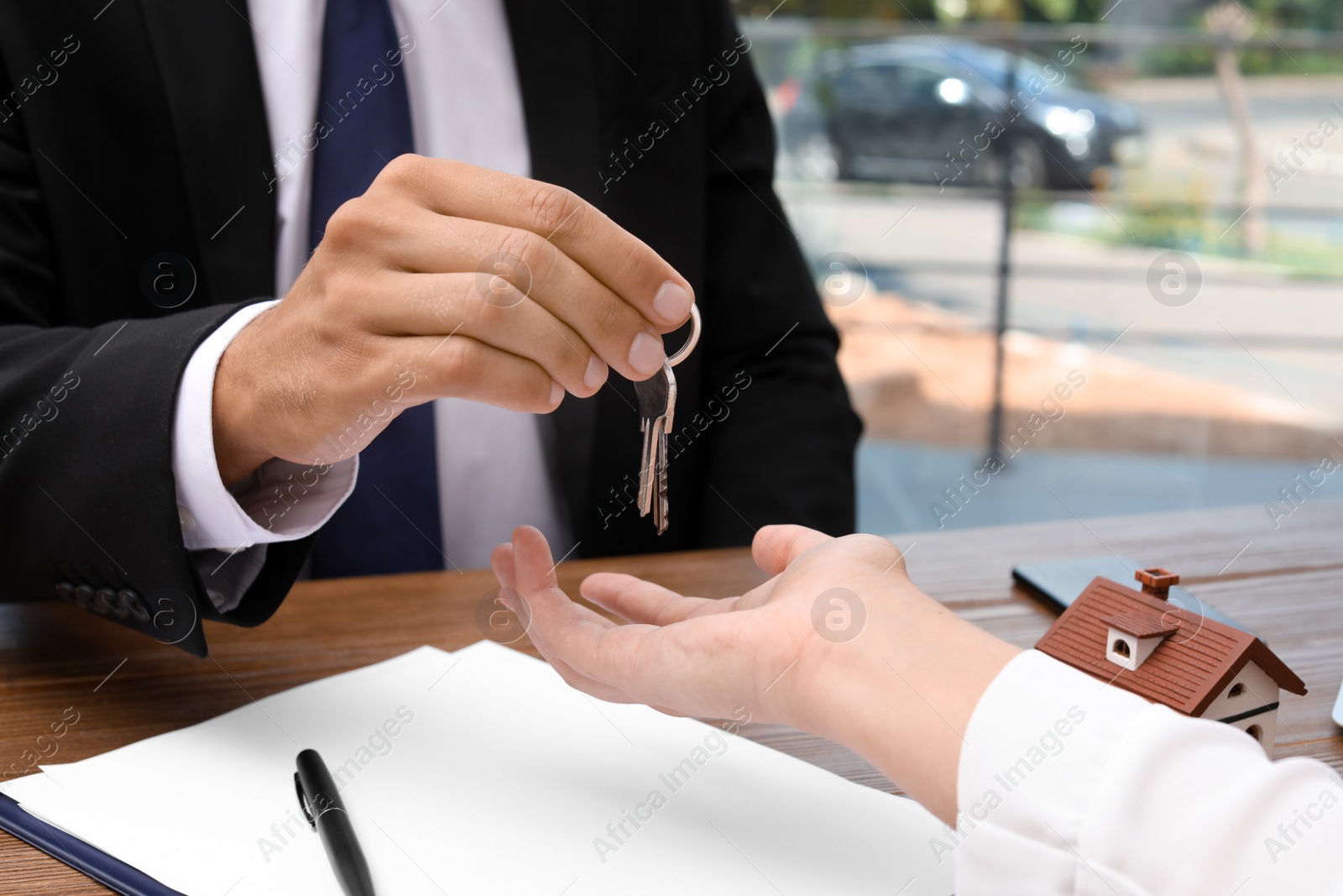 Photo of Real estate agent giving keys to woman at table