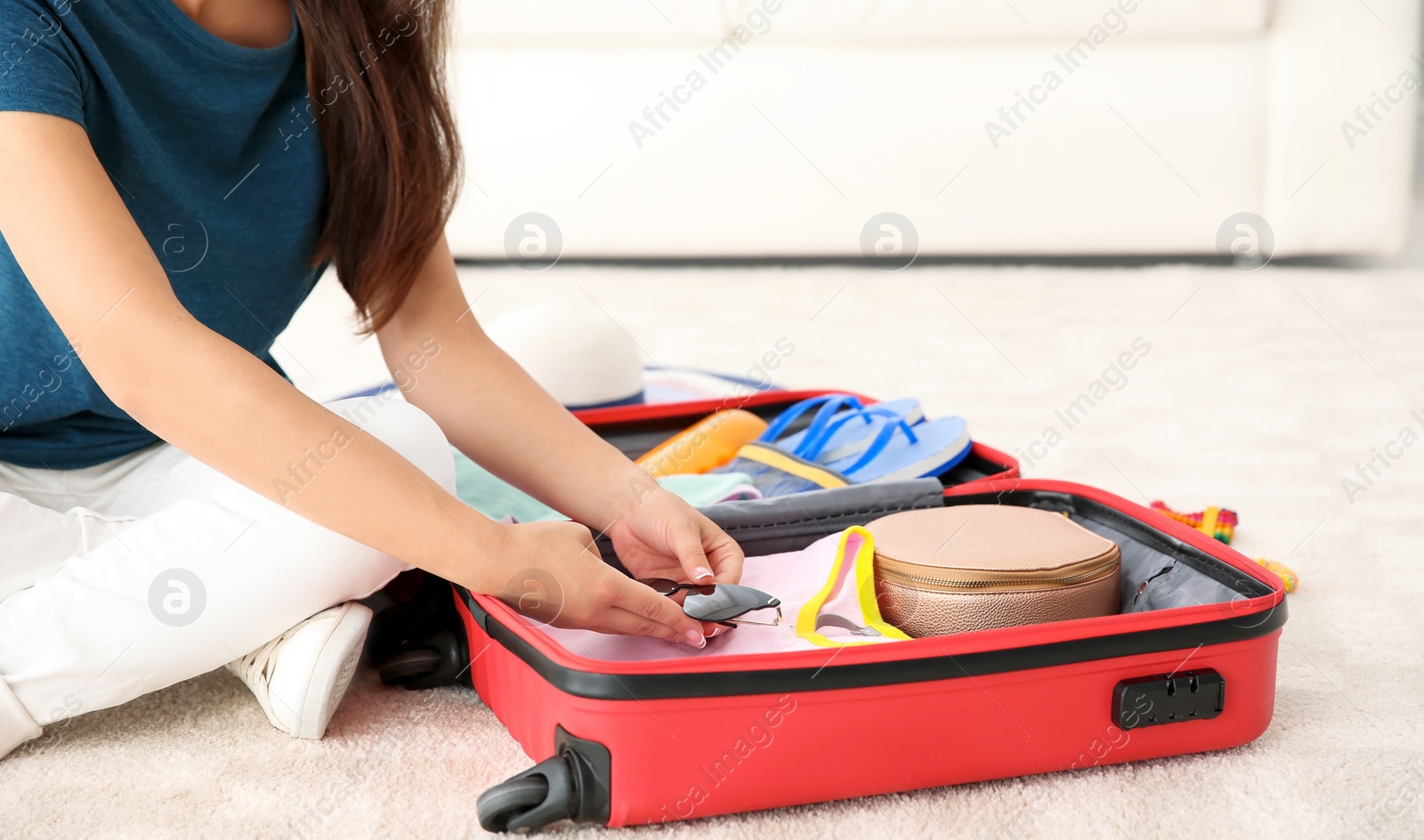 Photo of Young woman packing suitcase for summer journey at home