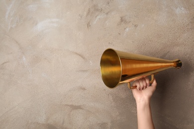 Photo of Woman holding retro megaphone near color wall