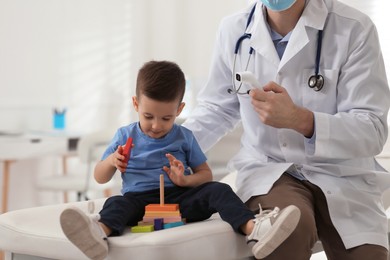 Photo of Pediatrician checking little boy's temperature at hospital