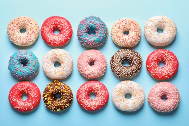 Delicious glazed doughnuts on color background, top view