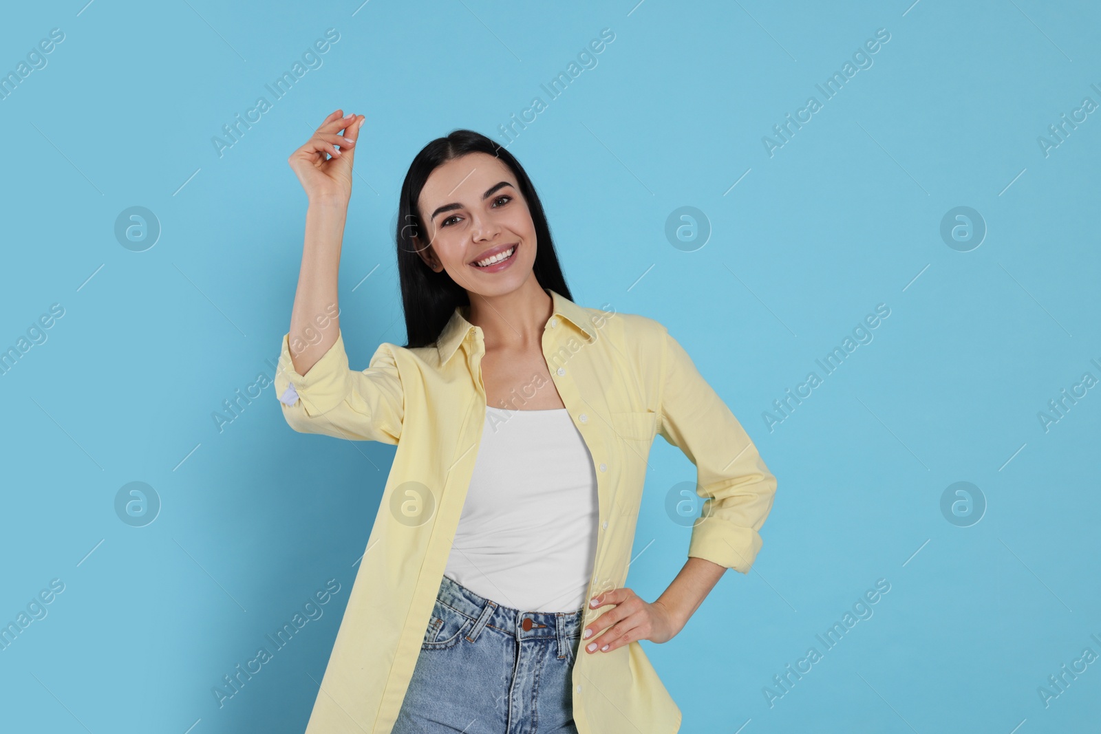Photo of Young woman snapping fingers on light blue background. Space for text