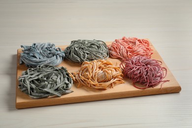 Photo of Rolled pasta painted with food colorings on white wooden table