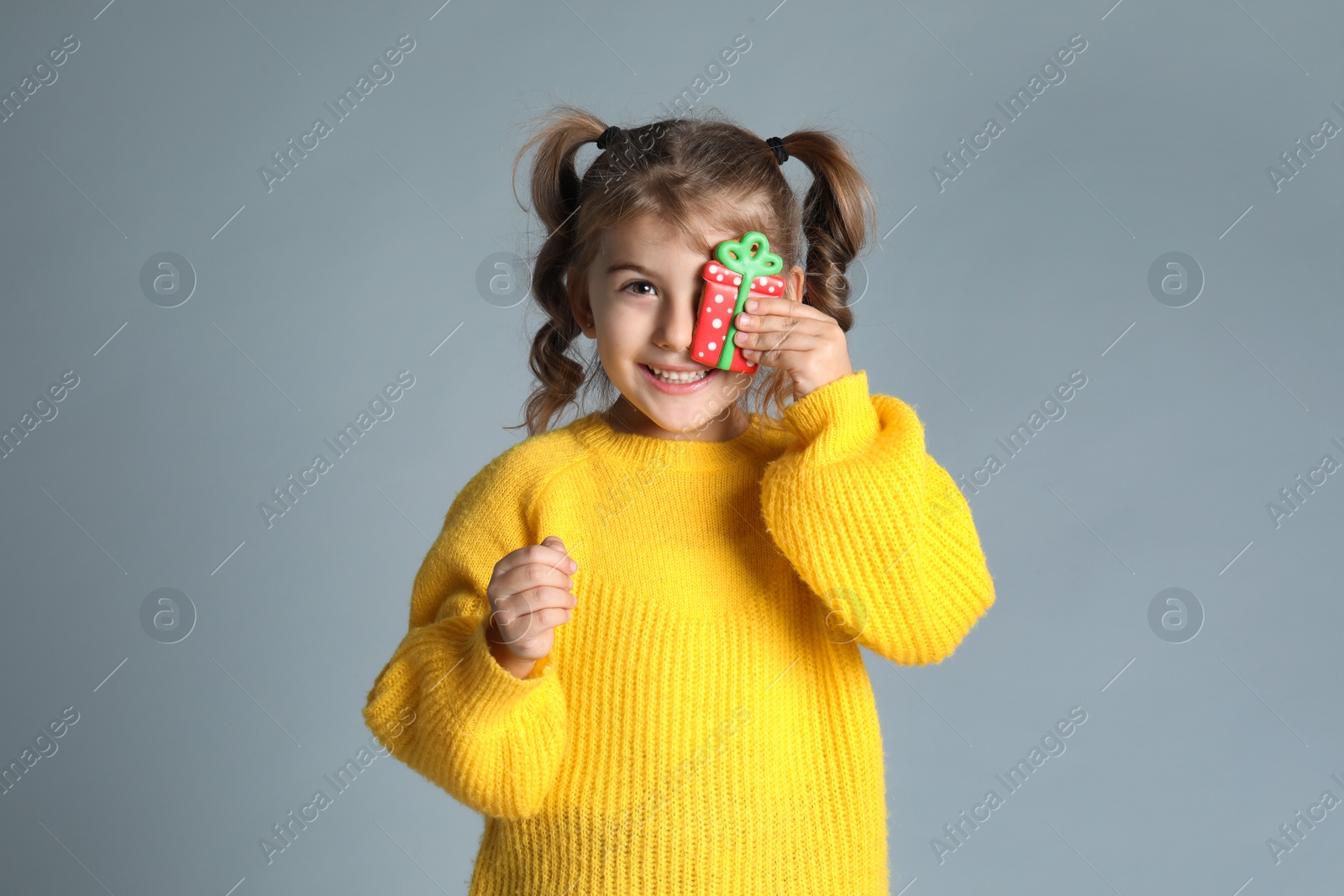 Photo of Cute little girl with Christmas gingerbread cookie on light grey background