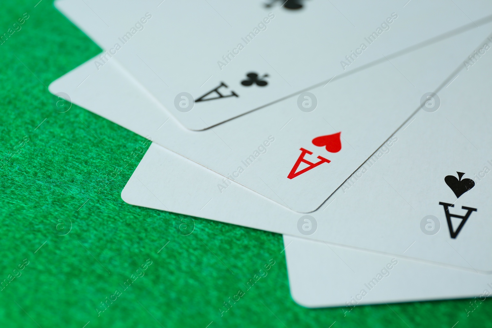 Photo of Playing cards with three of kind combination on green table, closeup