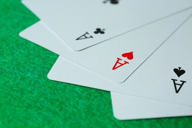 Playing cards with three of kind combination on green table, closeup