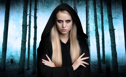 Image of Witch wearing black mantle in foggy forest. Scary fantasy character