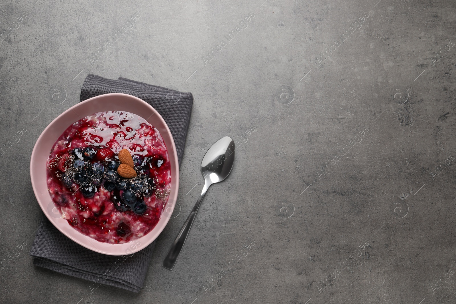 Photo of Tasty oatmeal porridge with toppings on grey table, flat lay. Space for text