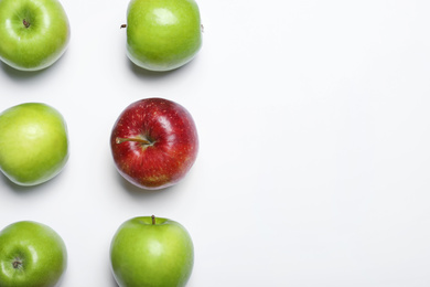 Photo of Red apple among green ones on white background, top view