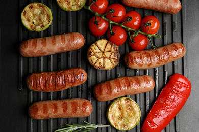 Cooking delicious fresh sausages with vegetables on modern grill, flat lay