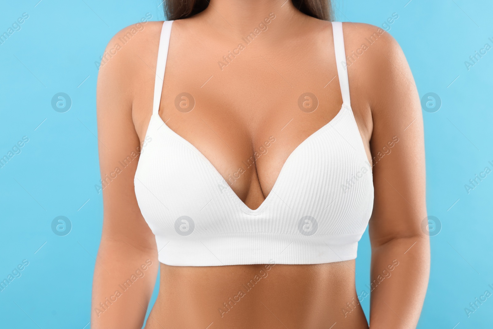 Photo of Woman with beautiful breast on light blue background, closeup