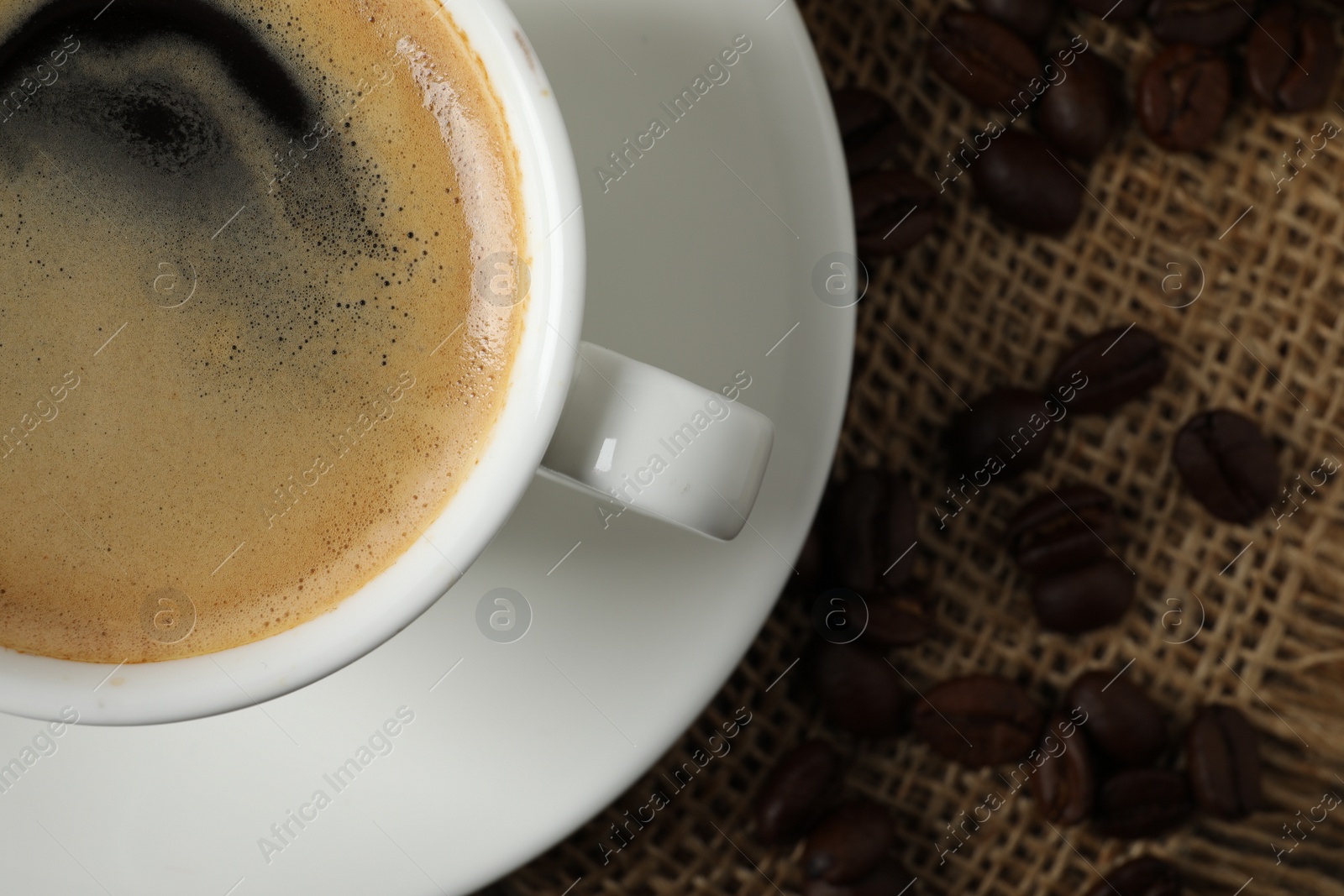 Photo of Cup of aromatic coffee on wooden table, top view. Space for text