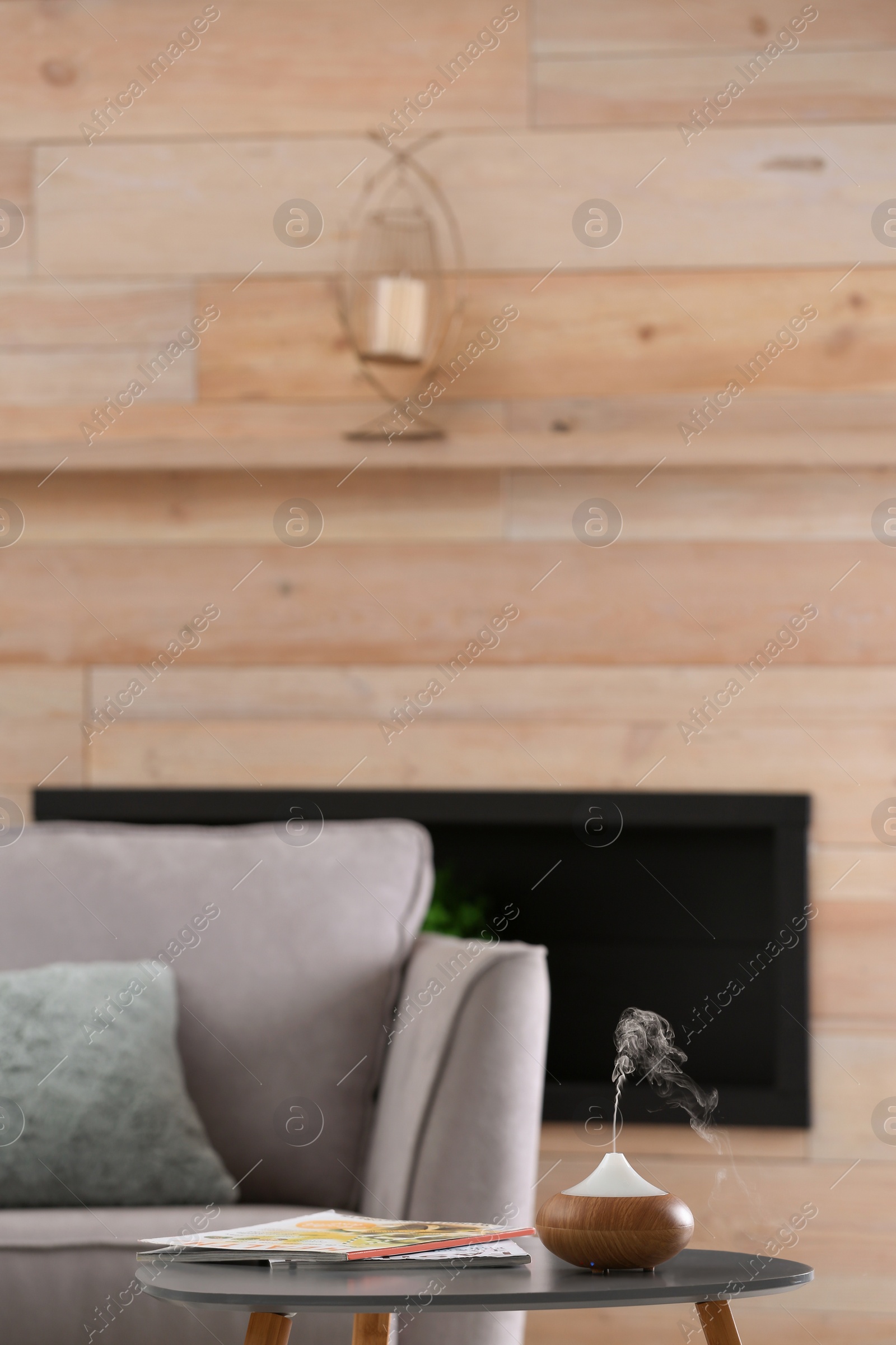 Photo of Stylish room interior with aroma oil diffuser lamp on table