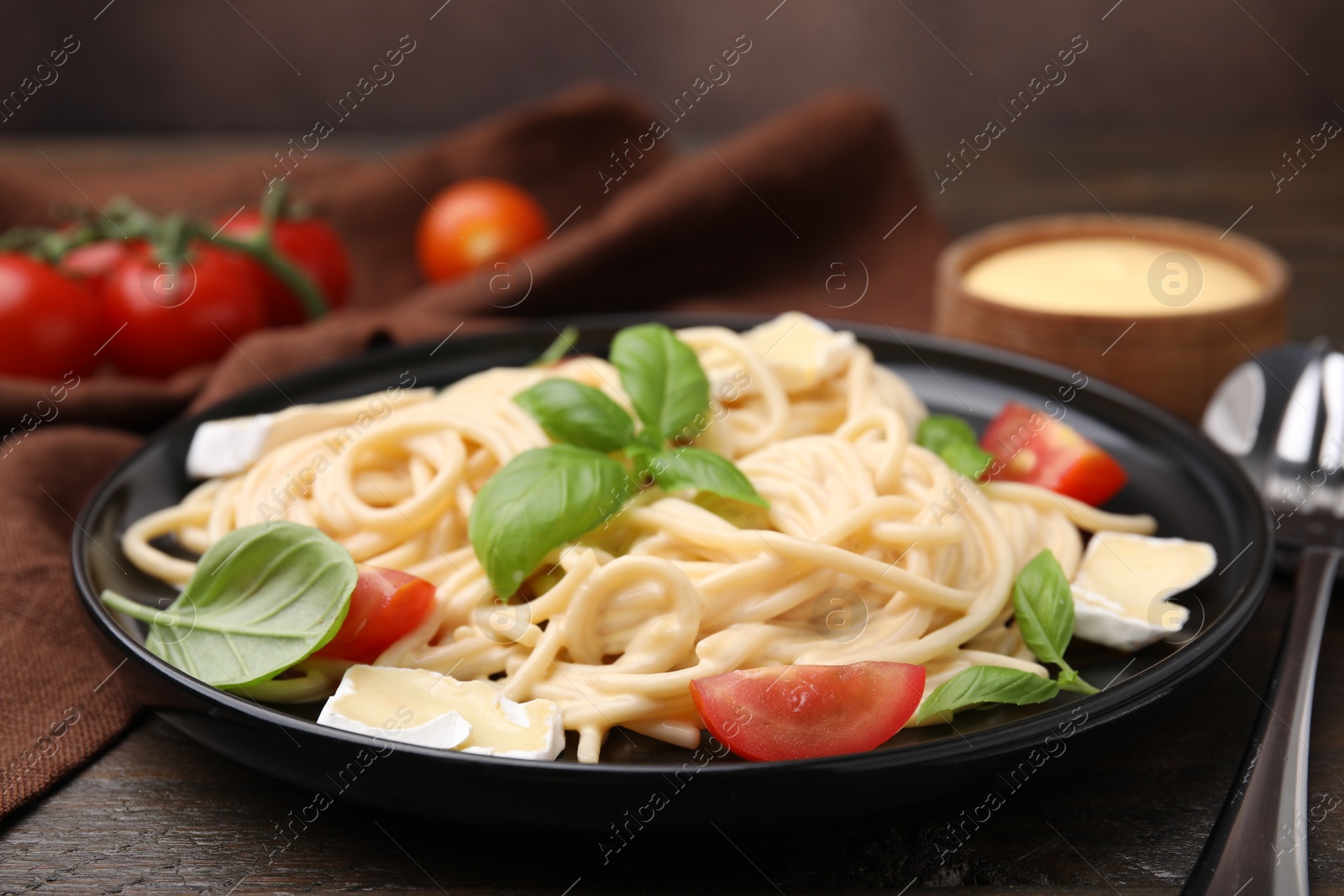 Photo of Delicious pasta with brie cheese, tomatoes and basil leaves on table, closeup