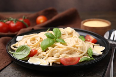 Photo of Delicious pasta with brie cheese, tomatoes and basil leaves on table, closeup