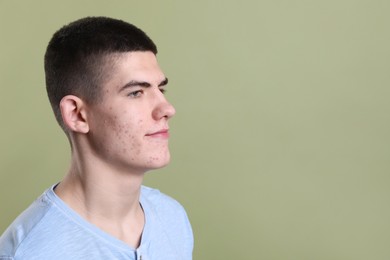 Photo of Young man with acne problem on olive background. Space for text