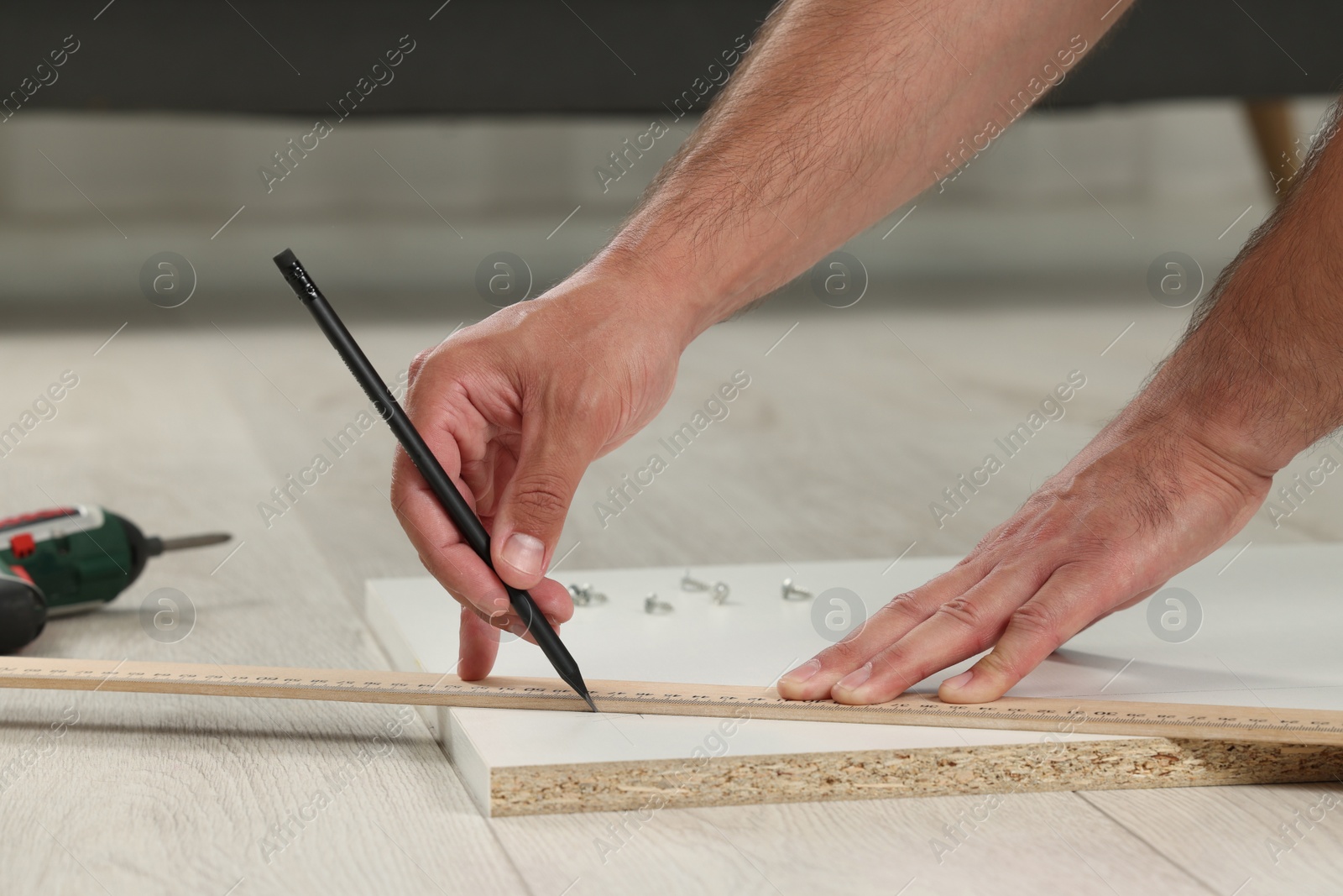 Photo of Man making mark on white board indoors, closeup. Furniture assembly