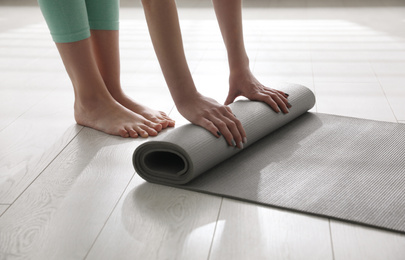 Photo of Woman rolling her mat on floor in yoga studio, closeup