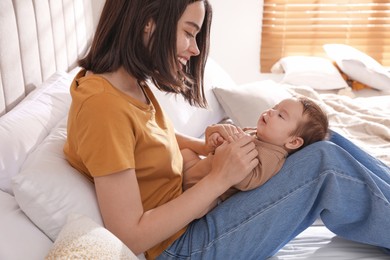 Photo of Happy young mother with her cute baby on bed at home