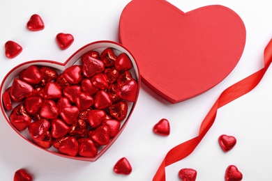 Photo of Box of heart shaped chocolate candies and ribbon on white background, top view