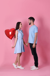 Lovely couple with heart shaped balloon on pink background. Valentine's day celebration